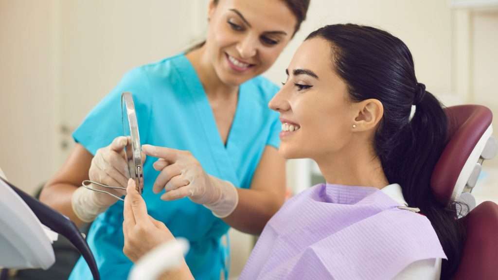 A woman in a dentist's chair looks in the mirror after a teeth cleaning in Fair Oaks, CA.